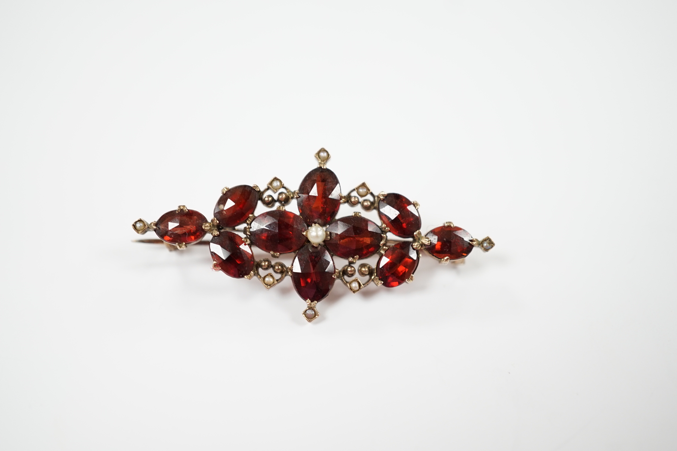 A Victorian yellow metal, garnet and seed pearl cluster set brooch, 44mm, gross weight 4.8 grams.